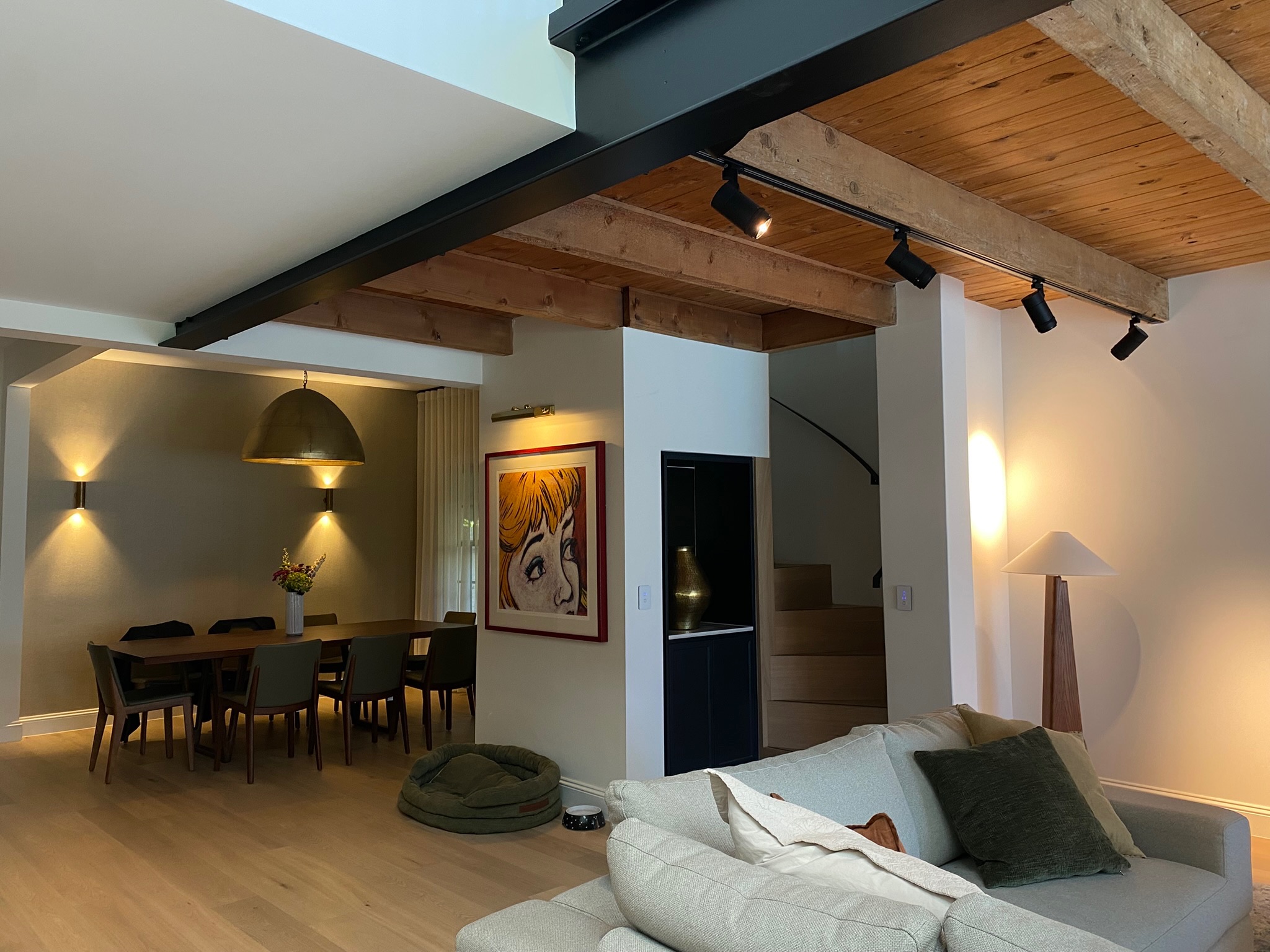 Warmly lit open-plan living and dining pavilion with layered pendant, sconce and track lighting